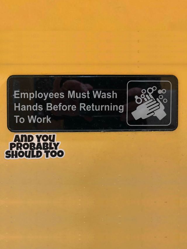 Black sign on a yellow wall with a sticker below it reading “And you probably should too”