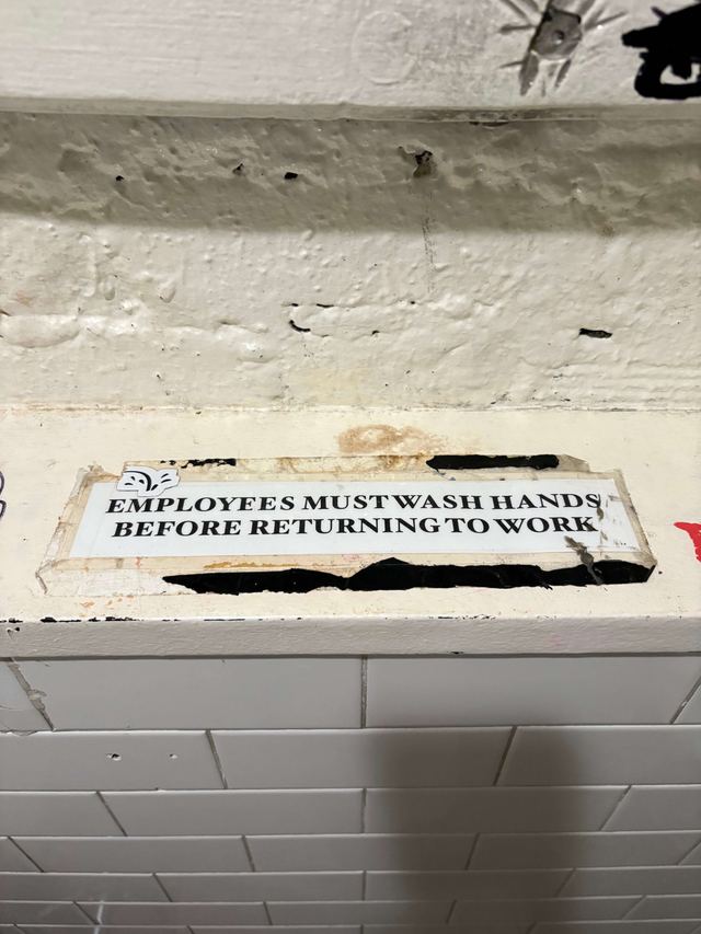 Worn white sign with black serif lettering on a painted brick ledge at Father Knows Best in Brooklyn